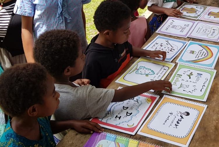 A group of children looking at a number of colourful books.